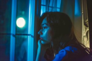 Woman looking out the window, feeling the effects of seasonal depression.